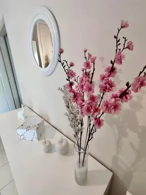 a vase with pink flowers on a table in front of a mirror at Tzitzifianaki Cozy Apartment in Chania Town