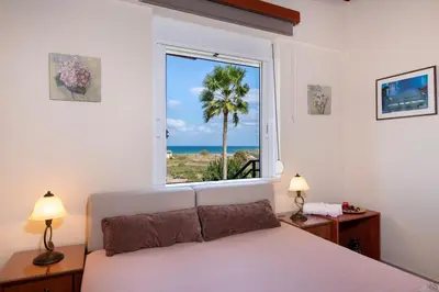 a bedroom with a large window with a view of the ocean at Socrates Holidays Apt 4 with Pool near the Beach in Kamisianá