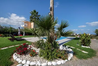 a garden with flowers and a palm tree next to a pool at Socrates Holidays Apt 4 with Pool near the Beach in Kamisianá