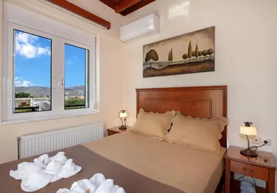 a bedroom with a bed and two windows at Socrates Holidays Apt 4 with Pool near the Beach in Kamisianá