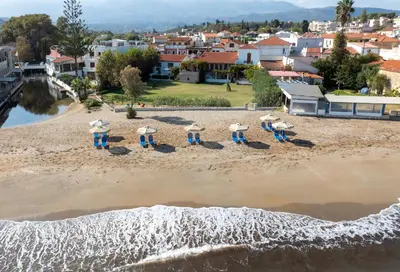 a group of people standing in the sand on a beach at Ismini Apartments in Kalyves