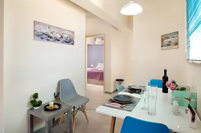 a dining room with a white table and blue chairs at Melina Apartments in Chania Town