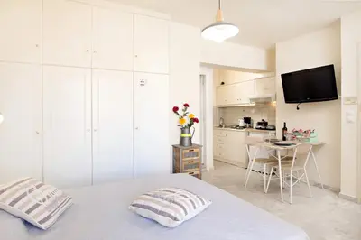 a white bedroom with a bed and a kitchen at Melina Apartments in Chania Town