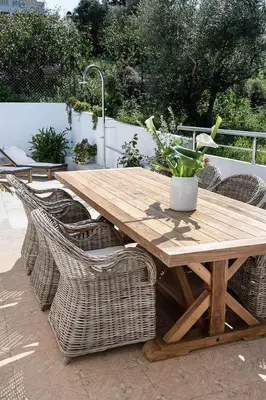 a wooden table with wicker chairs and a potted plant at Anemone Holiday Apartment in Kato Daratso