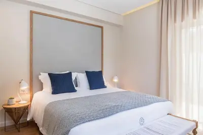 a bedroom with a large white bed with blue pillows at Anemone Holiday Apartment in Kato Daratso