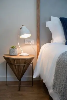 a lamp on a wooden table next to a bed at Anemone Holiday Apartment in Kato Daratso