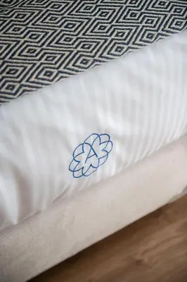 a white bed with a blue flower on the sheets at Anemone Holiday Apartment in Kato Daratso