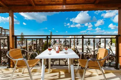 a white table with glasses of wine on a balcony at Evelinas House Platanias in Plataniás