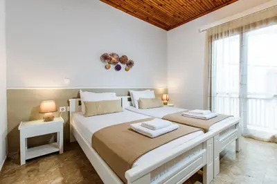 a white bedroom with two beds and a window at Evelinas House Platanias in Plataniás