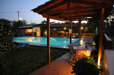 a swimming pool with a pergola next to a house at Argo Apartments in Kato Daratso
