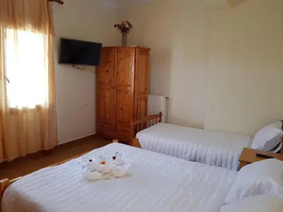 a hotel room with two beds and a television at Eftihia's Traditional House in Loúlos