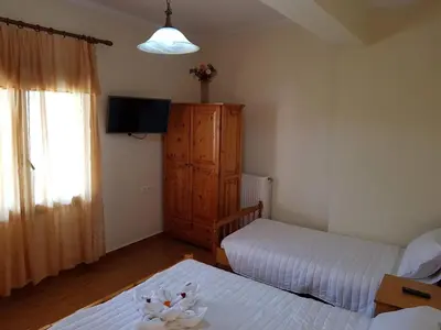 a small bedroom with two beds and a television at Eftihia's Traditional House in Loúlos