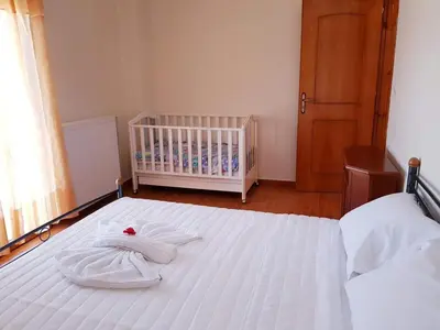 a white bed with a crib in a bedroom at Eftihia's Traditional House in Loúlos