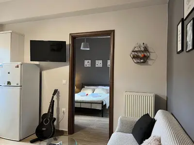a living room with a guitar and a bedroom with a bed at Antigoni's Studio Cozy Private Apartment in Kissamos