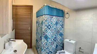 a bathroom with a blue shower curtain and a toilet at Antigoni's Studio Cozy Private Apartment in Kissamos