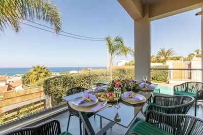 a table on a balcony with a view of the ocean at Superior Villa Kleanthi in Stalos