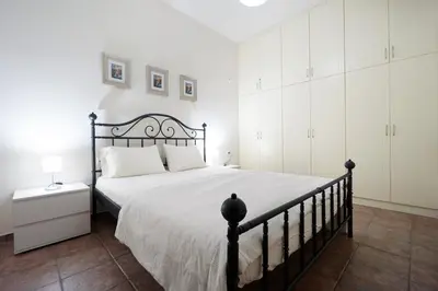 a bedroom with a black bed and white cabinets at Sunny Apartment in Daratso
