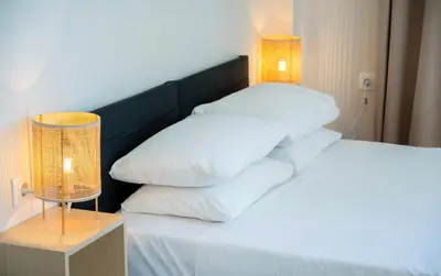 a bedroom with a bed with white pillows and a lamp at Mare I - studio in Old Harbor in Chania Town