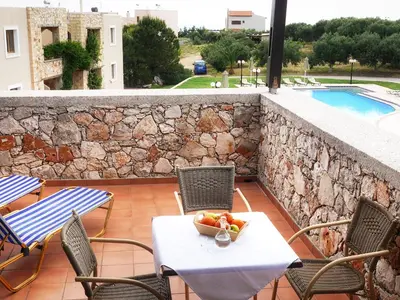 a table and chairs with a bowl of fruit on a patio at Areti Aparthotel in Áptera