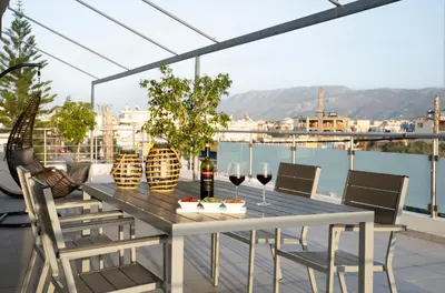 a table with wine glasses and chairs on a balcony at Amaen Apartment in Chania Town
