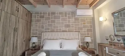 a bedroom with a bed and a stone wall at Elena Villa in Kissamos