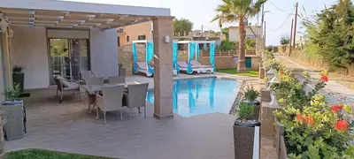 a patio with a table and chairs next to a pool at Elena Villa in Kissamos