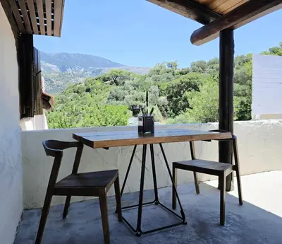 a wooden table and two chairs on a balcony at Monastery Estate Guesthouse in Sougia