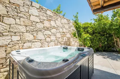 a hot tub in front of a stone wall at Monastery Estate Guesthouse in Sougia