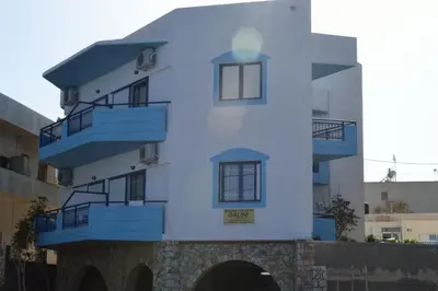 a white building with blue balconies on it at Galini Studios in Palaiochóra