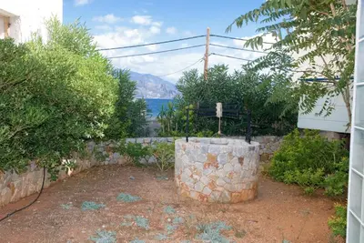 a stone barrel in a garden with a view of the water at Galini Studios in Palaiochóra