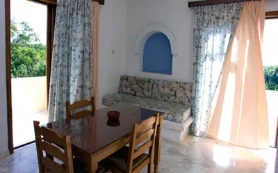 a dining room with a table and chairs and windows at Olga Suites in Maleme