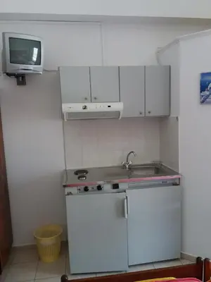 a kitchen with white cabinets and a sink and a tv at Oasis Studios in Palaiochóra