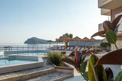 a resort with a pool and chairs and umbrellas at Hotel Haris on the beach in Agia Marina Nea Kydonias
