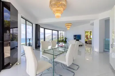 a dining room with a glass table and white chairs at Villa Dione Palace in Falasarna