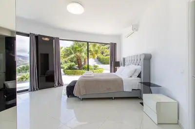 a white bedroom with a bed and a large window at Villa Dione Palace in Falasarna