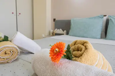 a teddy bear sitting on a bed with a flower at Elita beachfront in Chania Town