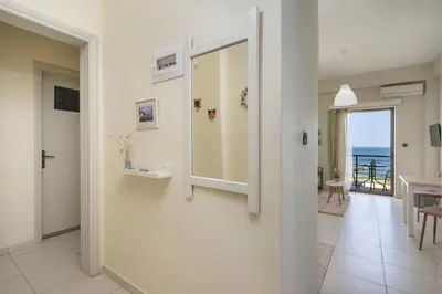 a white hallway with a mirror and a dining room at Elita beachfront in Chania Town