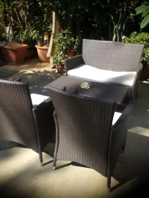 two wicker chairs and a table on a patio at Leonidas Rooms in Plataniás