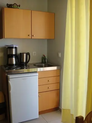 a kitchen with a sink and a stove and cabinets at Leonidas Rooms in Plataniás