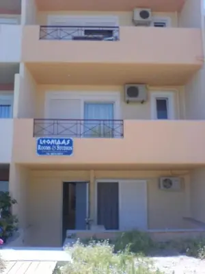 a building with a balcony and a sign on it at Leonidas Rooms in Plataniás