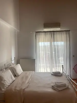 a bedroom with a large bed with a window at Thea Artemis in Kato Daratso