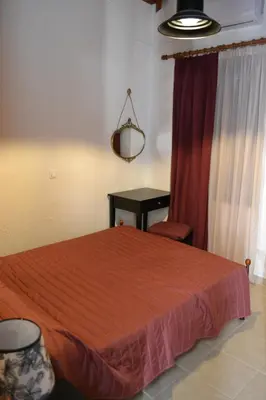 a bedroom with a red bed and a table at Villa Eternity in Alikampos