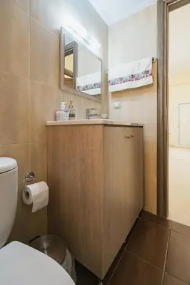 a bathroom with a sink and a toilet and a mirror at Spacious Home with Parking in Chania Town