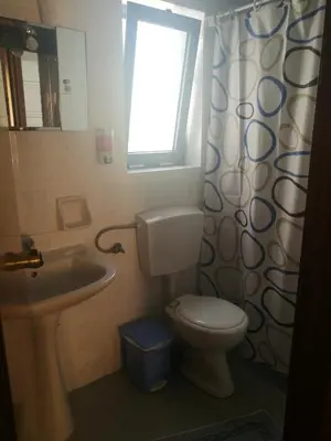 a bathroom with a toilet and a sink and a window at Adamas Rooms in Palaiochóra