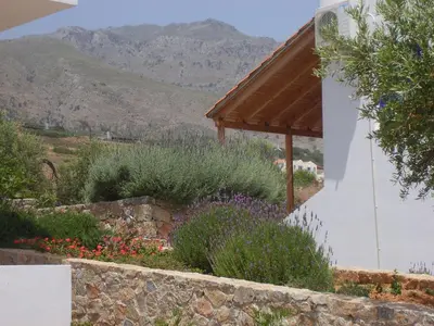 a garden in front of a building with mountains in the background at Studios Fokies in Khóra Sfakíon