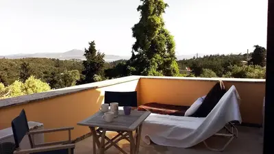 a balcony with a table and a bed and a couch at Crete holiday rental small village close to beaches -sharing a large pool in Vamos