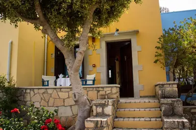 a yellow house with stairs and a tree at Crete holiday rental small village close to beaches -sharing a large pool in Vamos