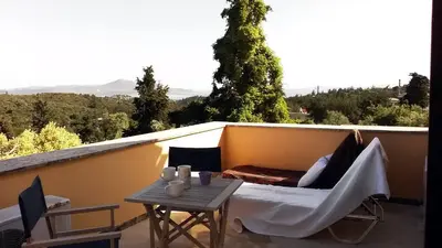 a balcony with a table and a bed and a table sidx sidx at Crete holiday rental small village close to beaches -sharing a large pool in Vamos