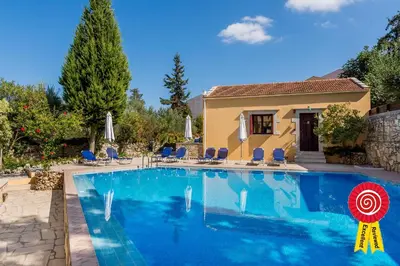a swimming pool with chairs and a house at Crete holiday rental small village close to beaches -sharing a large pool in Vamos