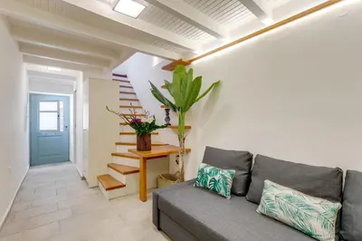 a living room with a gray couch and stairs at La Barchetta Old Town Home with Seaview in Chania Town